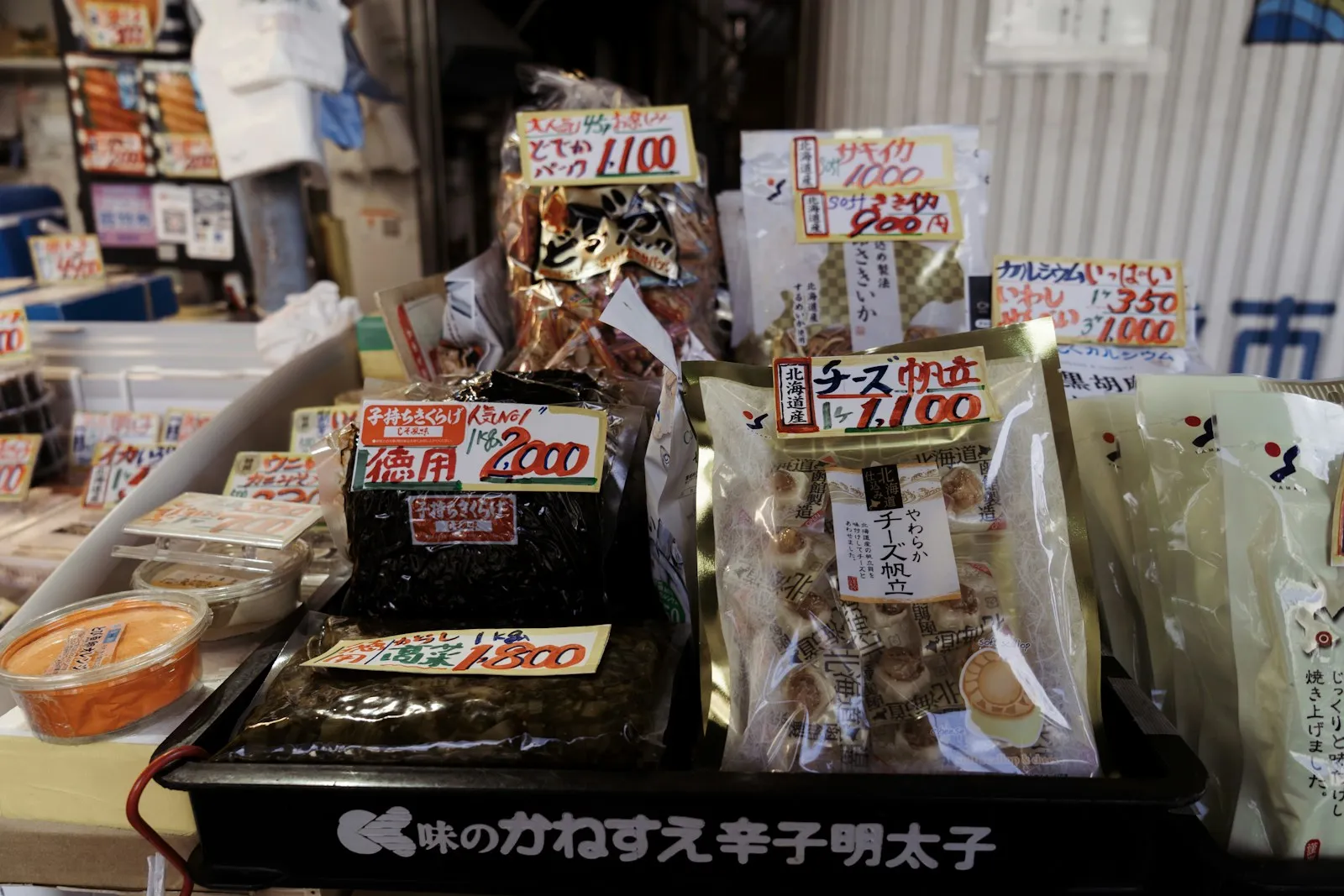 Packaged Japanese snacks with handwritten price tags on a shop shelf.