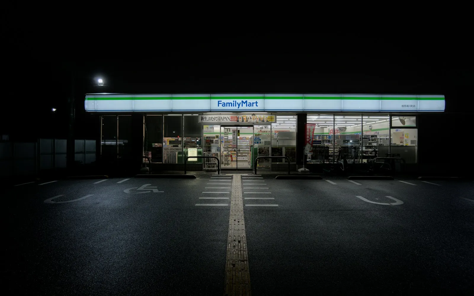 A Japanese convenience store lit up at night on a quiet street.
