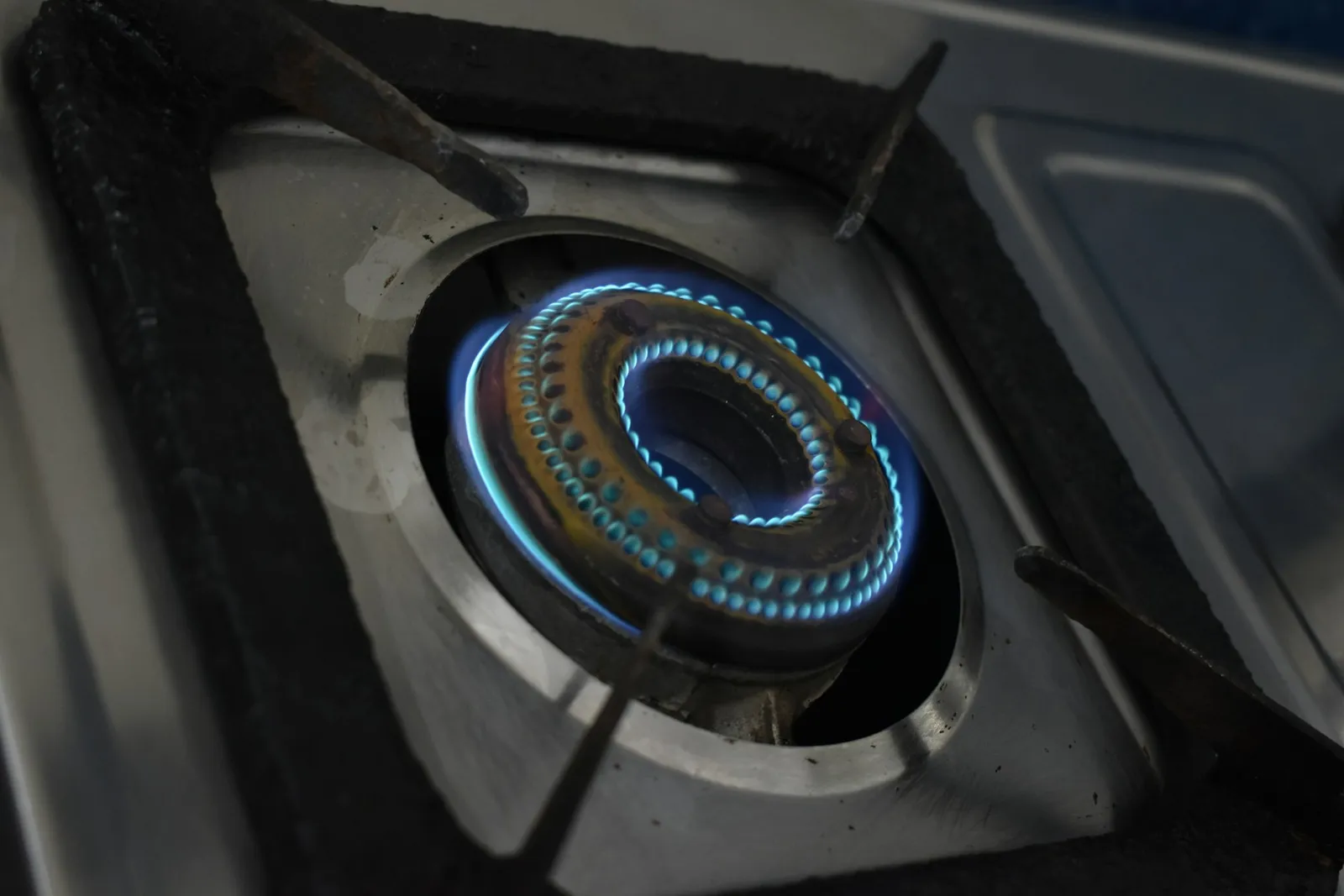 A close-up of a blue gas flame burning on a stove burner.