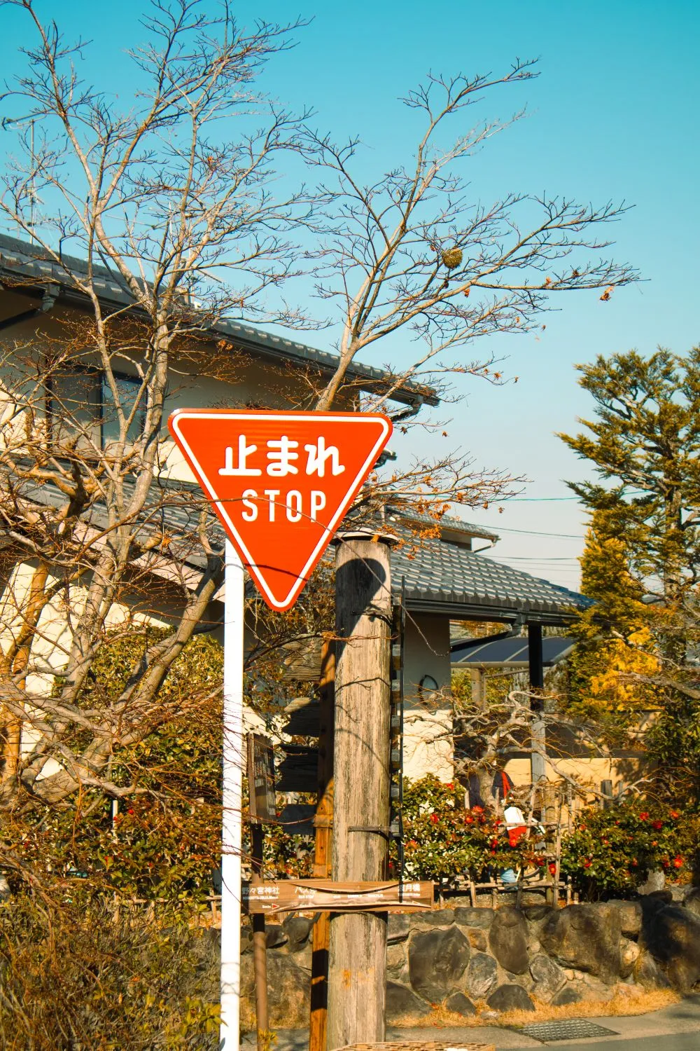 A red triangular Japanese stop sign standing in a quiet residential street.