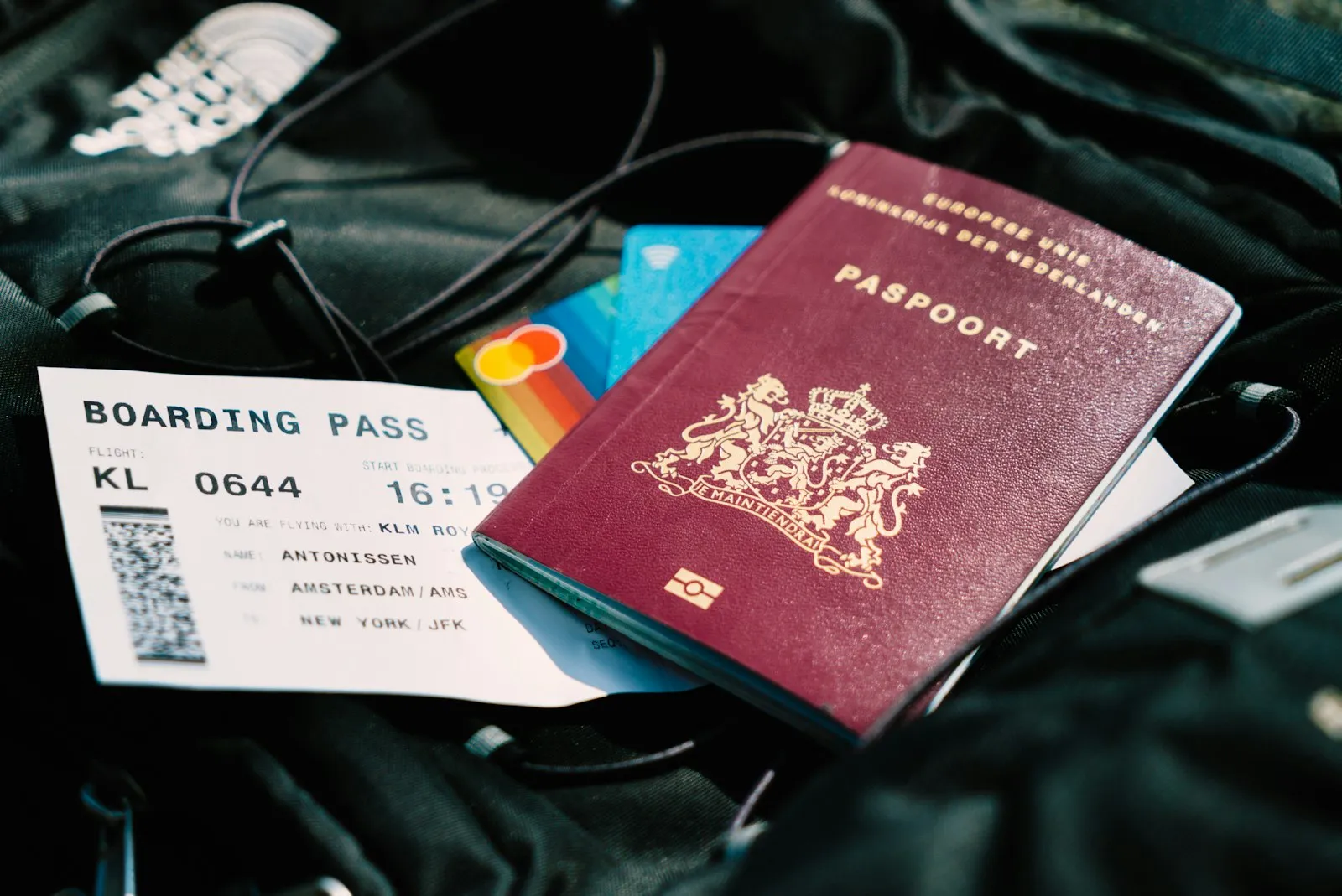 A passport, a boarding pass and bank cards resting on a travel bag.