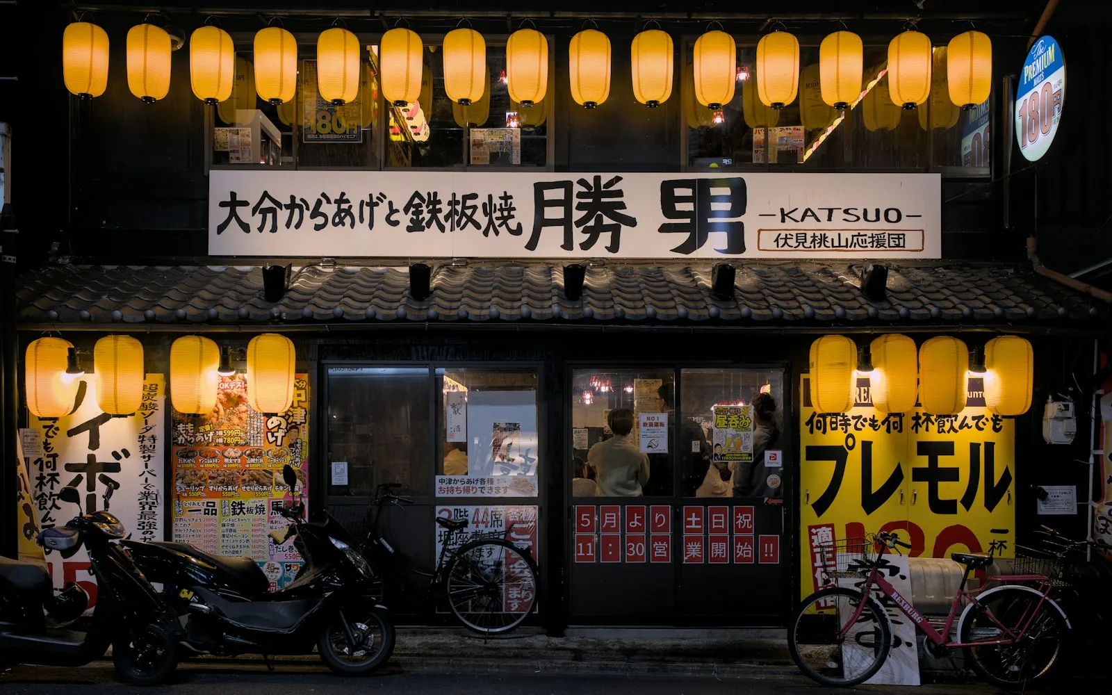 The lantern-lit front of a Japanese restaurant at night.