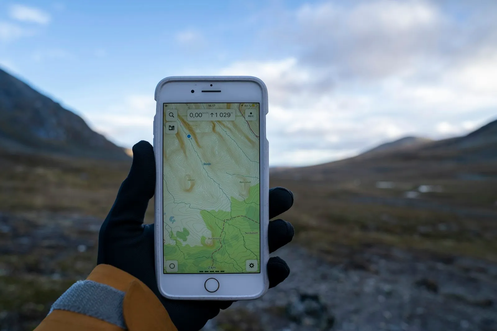 A gloved hand holding a smartphone that is showing a map.