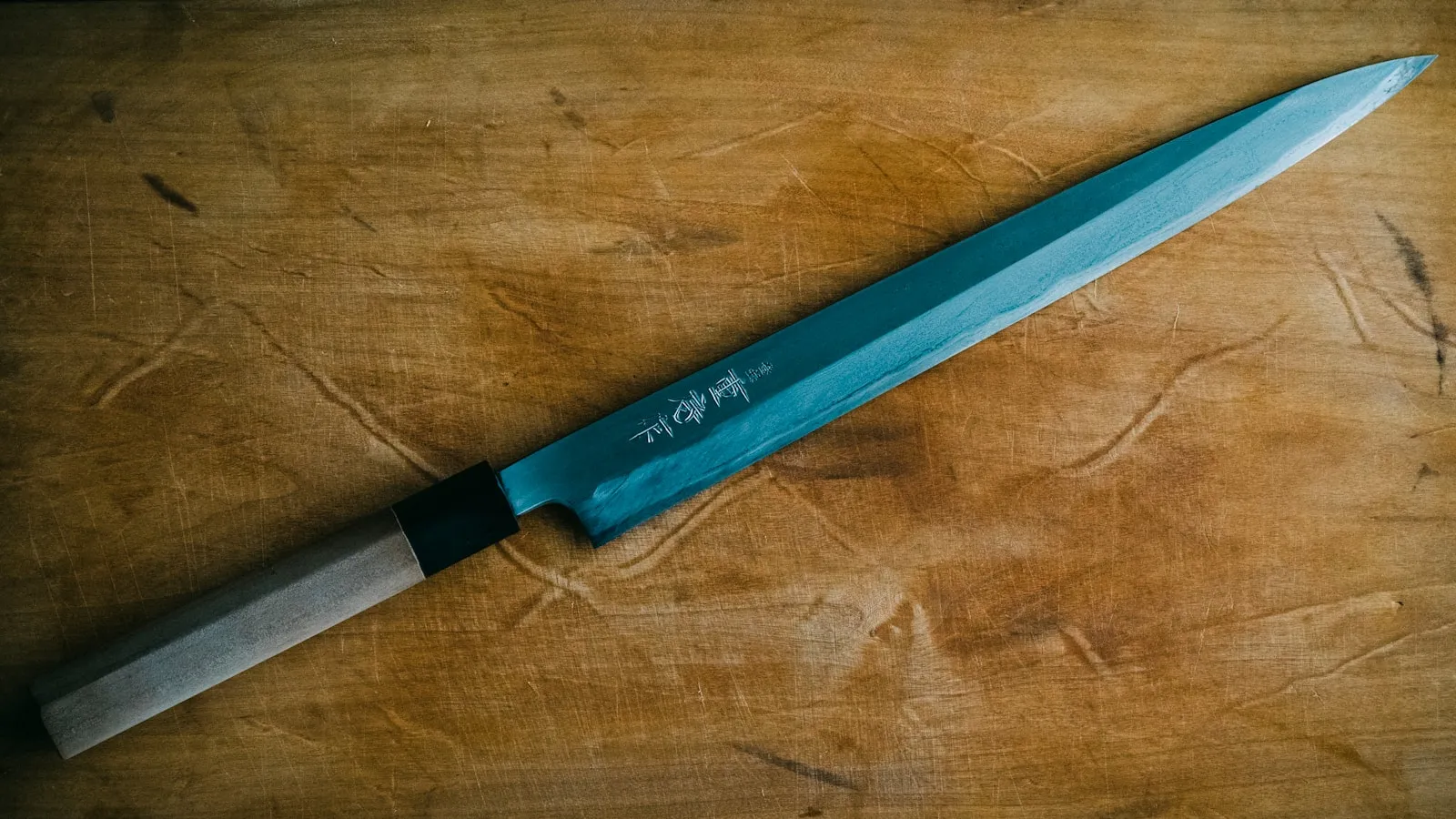 A close-up of a gray stainless steel kitchen knife blade.