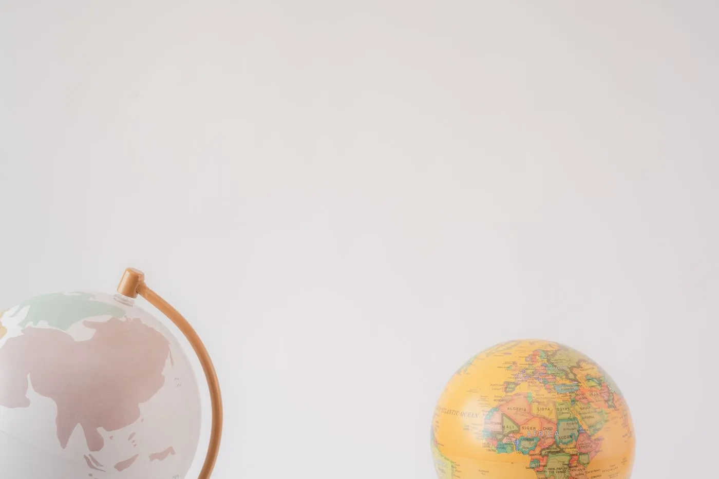Two decorative desktop globes on a white background, one showing Asia and Europe, the other showing Africa with country names labeled.