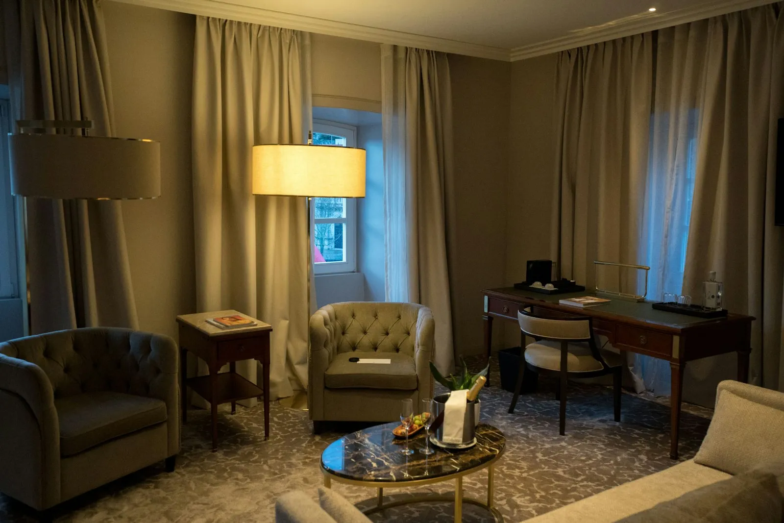 A hotel room with a writing desk, armchairs and a floor lamp.