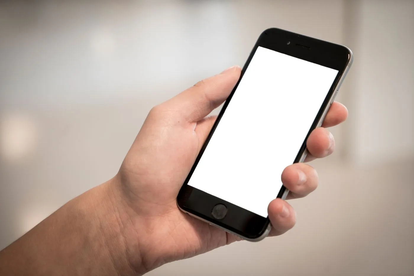 A hand holding a smartphone with a blank white screen.