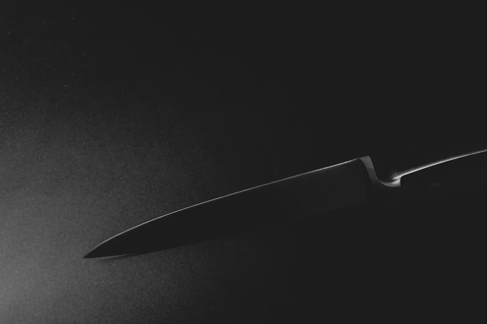 A close-up of a knife tip against a dark background.