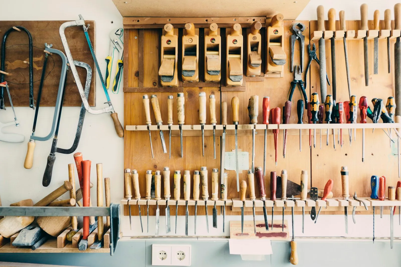 A workshop wall rack holding rows of hand tools.